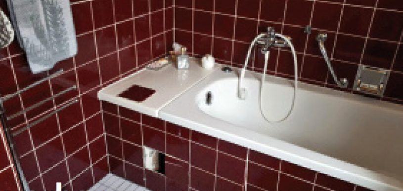 Dasselbe Bad vor der Sanierung: dunkelrote Fliesen und alte Wanne