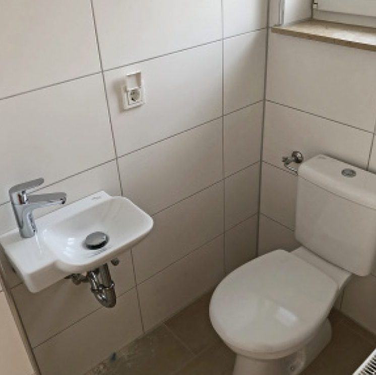 Gäste-WC nach der Modernisierung: helle Fliesen, neues Waschbecken
